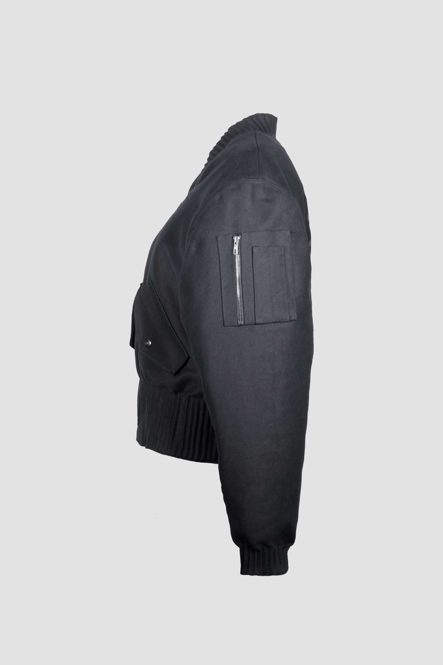 A black bomber jacket "Alles Von Hier" (Eveyrhting from Here) by Esther Perbandt, shown from a side profile view against a solid light gray background.