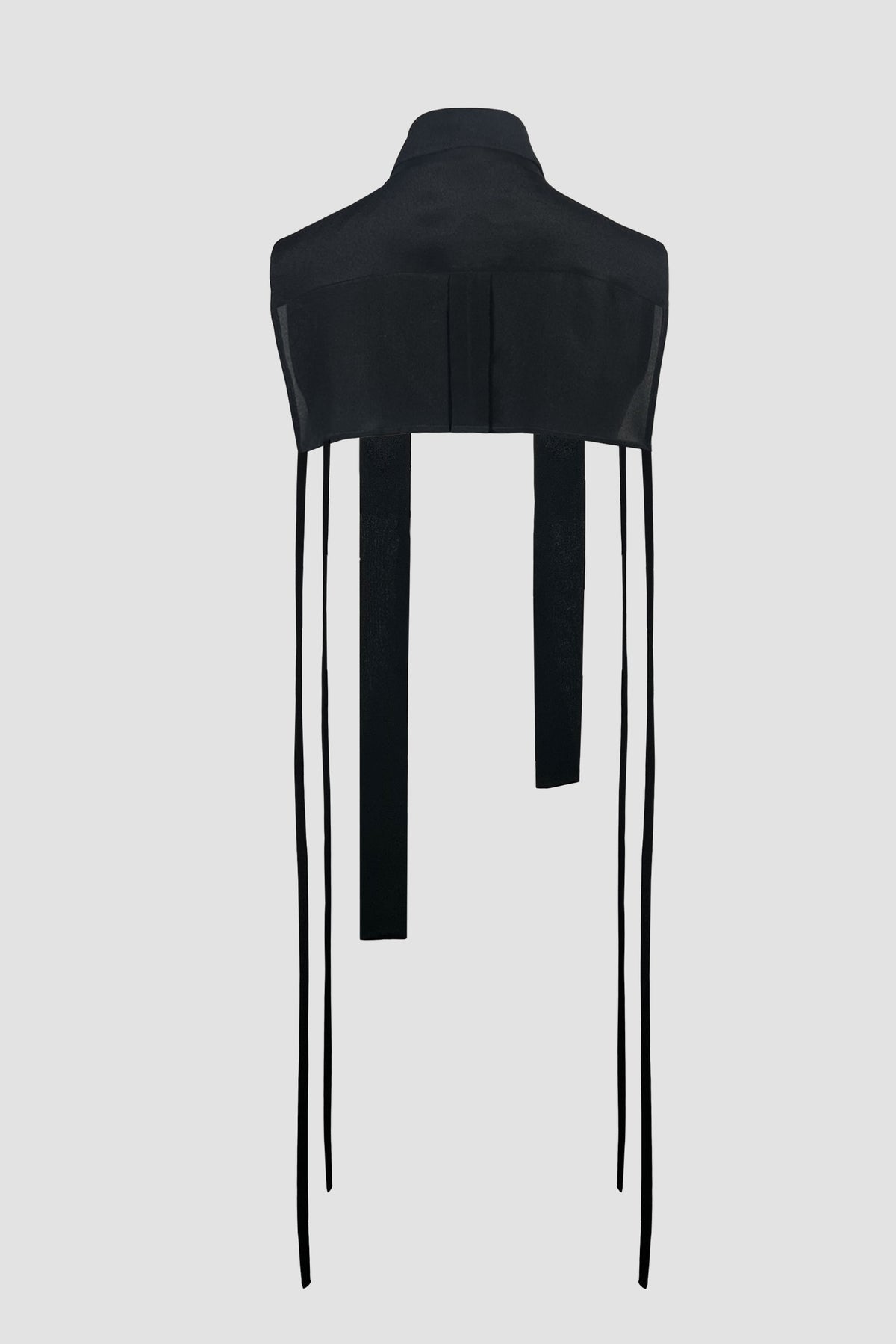 A black sleeveless top with a high mock neck and long hanging tie straps, shown on a plain light gray background.